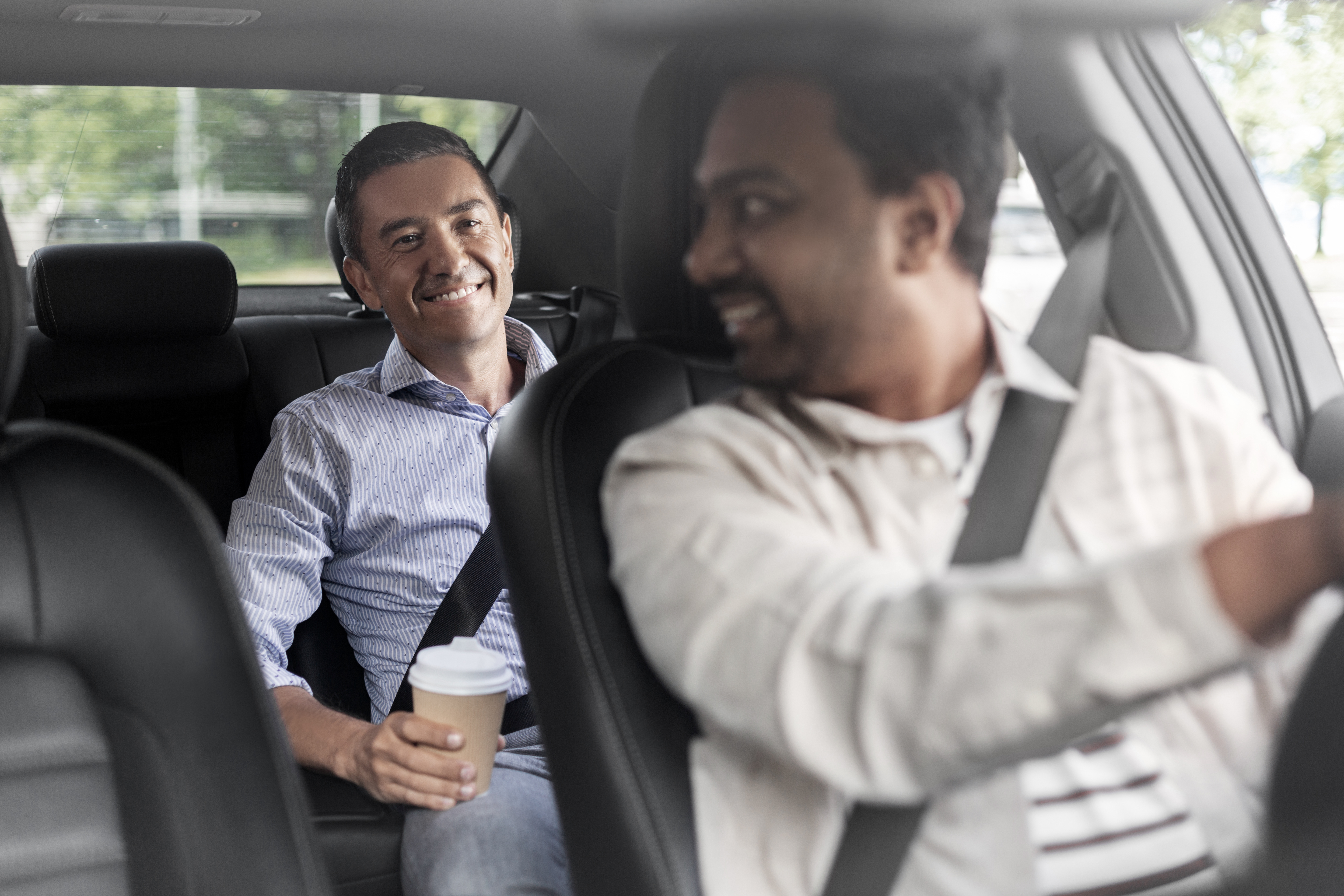 transportation, vehicle and people concept - happy smiling middle aged male passenger with coffee cup talking to taxi car driver male passenger with coffee talking to car driver